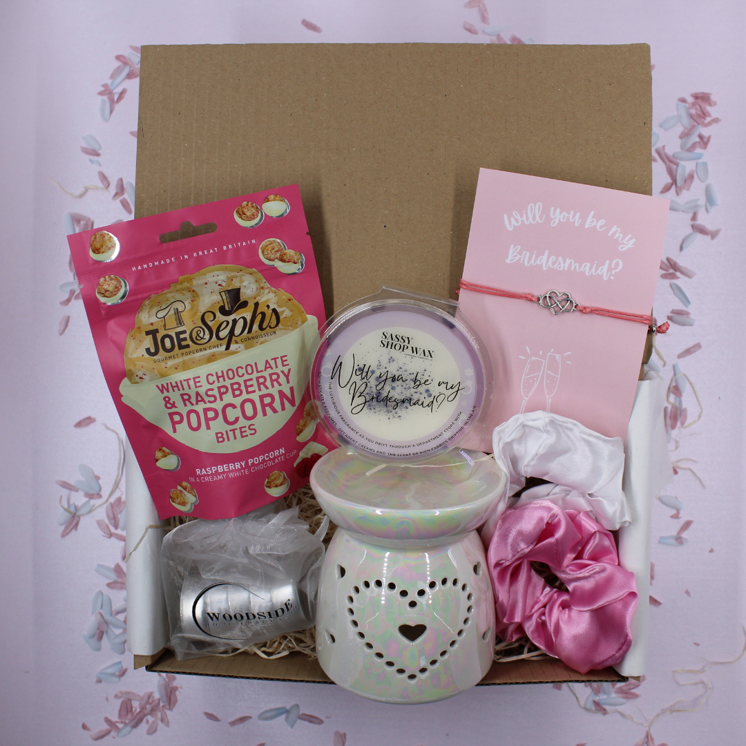 Gift set with pop corn, scented lamp, and 'Will you be my bridesmaid?' card on a white background.