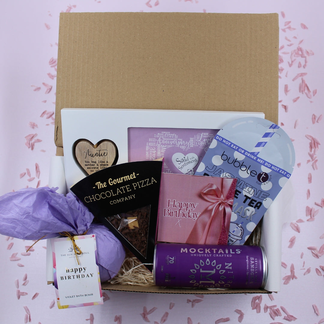 Gift box with birthday-themed items on a pink background