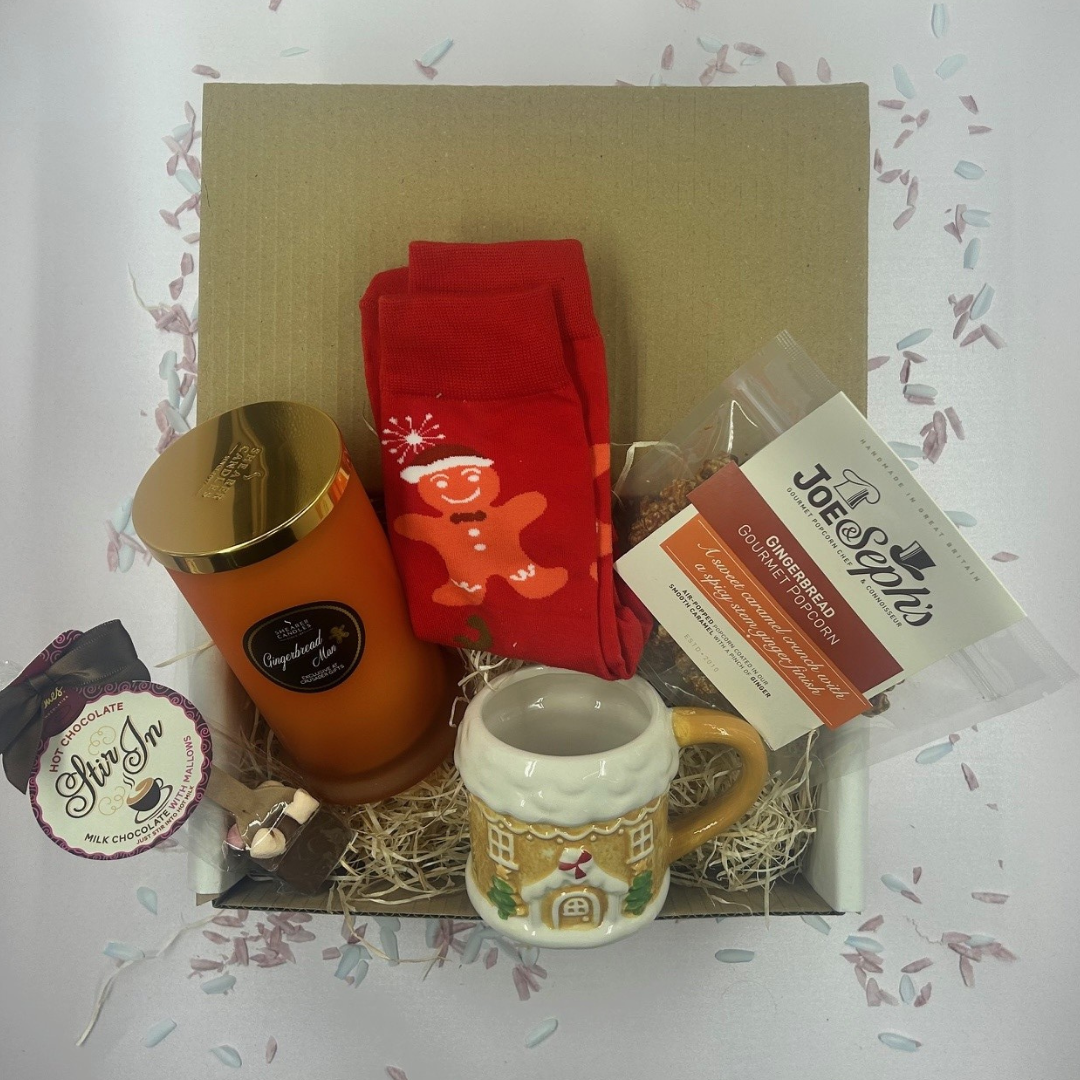 Christmas gingerbread treat box with candle, mug, socks, popcorn, and hot chocolate